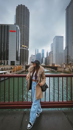 a woman is standing on a bridge near the water