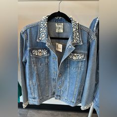 a denim jacket with studded shoulders hanging on a rack