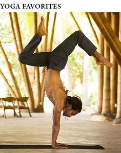 a man doing a handstand on a yoga mat in front of bamboo trees