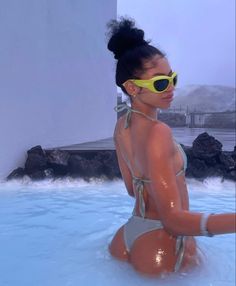 a woman in a bathing suit and sunglasses sitting in a hot tub with water around her