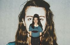 a woman with long hair standing in front of a white wall