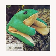 a green frog stuffed animal sitting on top of a tree