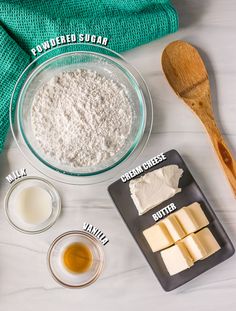 ingredients needed to make cheesecakes laid out on a white counter top, including butter, sugar and flour