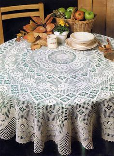 a table topped with a white doily covered table next to a basket of fruit