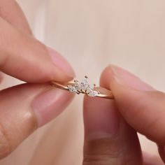 a person is holding a diamond ring in their left hand and touching it with the other hand