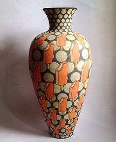 an orange and black vase sitting on top of a white table next to a wall