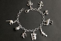 A collection of silver plated Australian wildlife themed charms have been dispersed around a shimmering silver plated bracelet chain in this handmade charm bracelet. This Australian wildlife charm bracelet is then completed with a lobster clasp and a 1/2 inch of chain at the end for adjustable sizing. Charms in this bracelet include a kangaroo charm, echidna charm, crocodile charm, koala charm, platypus charm, emu charm, wombat charm, gecko charm, and a sea turtle charm. ● Sizing ● To determine Nickel-free Silver Novelty Charms, Whimsical Silver Charms For Gifts, Whimsical Silver Dangling Charms, Themed Sterling Silver Charms, Personalized Silver Novelty Bracelets, Personalized Novelty Silver Bracelets, Themed Silver Charm Bracelet, Themed Silver Sterling Charms, Whimsical Nickel-free Silver Jewelry