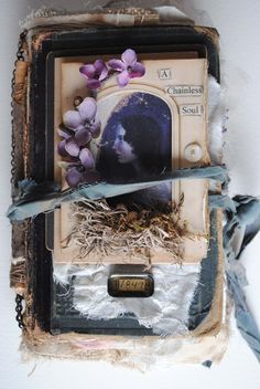 an altered photograph with flowers on it is hanging from a chain and has torn paper around the edges