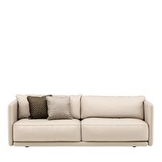 a white couch with some pillows on it's back and one pillow in the middle