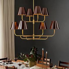 a chandelier hanging over a dining room table with place settings on the table