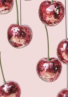 several shiny red cherries hanging on a pink background