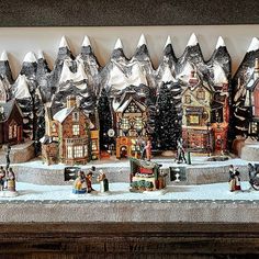 a group of christmas village figurines sitting on top of a table covered in tin foil