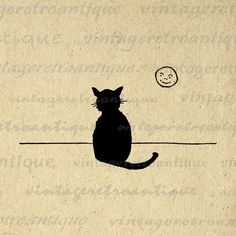 a black cat sitting on top of a piece of paper next to a small moon