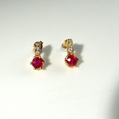 Here we have a gorgeous pair of natural earth mined vivid red ruby and sparkly diamond accent earrings crafted in solid 14K yellow gold. Together the pair weigh 3.2 grams approximately making them ideal for everyday wear. Each pretty earring measures approximately 1/2" long by 1/4" wide (12.6mm x 6.4mm). They are in lovely condition and are ready to gift or to wear. Each ruby measures respectively 5.14mm x 2.70mm and 5.08mm x 3.84mm. They weigh 0.52 carats and 0.84 carats. The diamond accents ea Luxury Red Ruby Earrings, Luxury Red Brilliant Cut Earrings, Ruby Earrings With Brilliant Cut In Fine Jewelry Style, Ruby Brilliant Cut Fine Jewelry Earrings, Fine Jewelry Ruby Earrings With Brilliant Cut, Ruby Earrings Brilliant Cut Fine Jewelry, Formal Red Diamond Earrings With Brilliant Cut, Yellow Gold Ruby Earrings With Brilliant Cut, Red Diamond Earrings For Formal Occasions