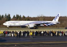 a large group of people standing in front of an airplane