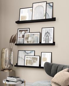 some black and white pictures hanging on the wall next to a gray chair in a living room