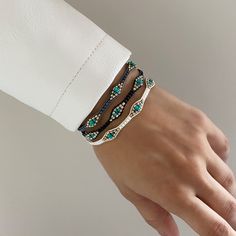 a woman's hand wearing a white leather bracelet with turquoise and brown beaded accents