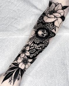 a black and white tattoo with flowers on the arm, done by an expert in body art