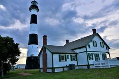 a white and green house next to a black and white lighthouse