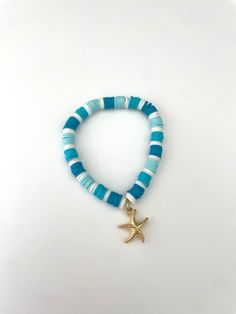 super cute clay beaded bracelet with 3 different  shades of blue , with a gold starfish in the middle! stretchy and durable Starfish Clay Bead Bracelet, Teal Clay Bead Bracelet, Blue Bracelets With Starfish Charm And Round Beads, Blue Bracelet With Starfish Charm And Round Beads, Blue Bracelets With Starfish Charm Ocean-inspired, Blue Beaded Bracelet With Starfish Charm, Adjustable Blue Bracelets With Starfish Charm, Ocean-inspired Blue Starfish Bracelets, Blue Beaded Bracelets With Starfish Charm