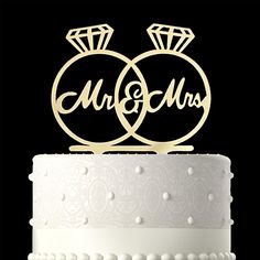 two wedding rings on top of a cake with the word mr and mrs written in cursive font