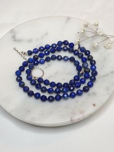 "Details: ☆ Gemstone- High quality Natural Lapis Lazuli, faceted round shape, 5mm  ☆ Closure- 925 Sterling silver, 12mm, a toggle clasp, twisted round ☆ Bead tip- 925 Sterling silver, 3mm ☆ Bead cap- 925 Sterling silver, 3mm, flower shape  The necklace length is 18.25\". It looks beautiful alone or layered with other necklaces.  It is a perfect gift for someone special or yourself.    All my jewelries are made with lots of love and care. Lapis Lazuli: Lapis Lazuli has many healing properties. This pretty indigo and gold gemstone is known for cleansing the throat and third eye Chakras and can be used to ward off physical attacks. As a stone geared towards wisdom and communication, Lapis Lazuli can also help connect you to clarity, integrity, and intuition." Elegant Lapis Lazuli Faceted Necklace, Lapis Lazuli Gemstone Beads Necklaces, Lapis Lazuli Gemstone Beads Necklace, Single Strand Lapis Lazuli Necklace, Faceted Sapphire Lapis Lazuli Necklace, Sapphire Faceted Beaded Necklace For Gift, Faceted Sapphire Beaded Necklace Gift, Beaded Necklace With Sterling Silver Clasp As Gift, Sapphire Faceted Beads Necklace For Gift