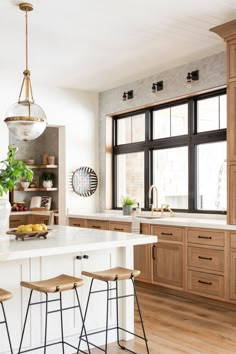 an open kitchen with wooden cabinets and stools in front of the countertop area