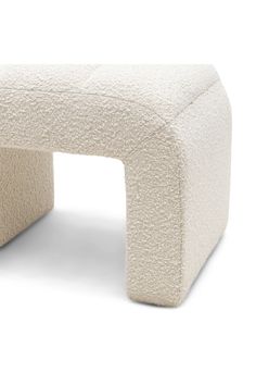 an upholstered bench made out of white wool with a rounded top and legs