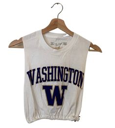 Vintage College Crop Tank Shop our vintage crop tanks that vary from a range of different graphics and colors All items you see are unique and the only one available in our shop Items fit true to size All items have been cut and altered into a crop tee All items are pre-worn, recycled, well kept items that are perfect for game days, college gatherings, every day wear, and more! If you have any questions about fit or the items, please send me a message before purchase. reworked adjustable drawstr Casual Tank Crop Top With Graphic Print, Casual Graphic Print Tank Crop Top, Retro Sleeveless Tank Top With Letter Print, Retro Sleeveless Letter Print Tank Top, Casual Letter Print Tank Crop Top, White Tank Crop Top For Streetwear, Cotton Graphic Print Crop Top For Sports, Collegiate Sleeveless Cotton Top, Collegiate Cotton Sleeveless Tank Top