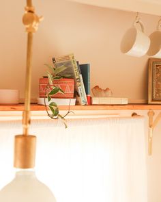 some books are sitting on a shelf next to a lamp and other items in a room