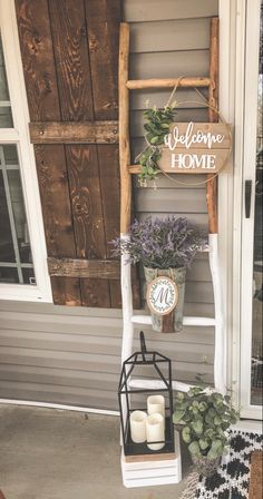 a welcome home sign hanging on the side of a house next to a ladder with candles