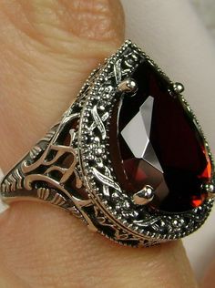 Red Garnet CZ Gemstone Teardrop RingTear Vic Design#D28 Inspired by Victorian and Art Deco designs, this high-quality filigree ring is handcrafted in sterling silver. This teardrop ring is set with an 8 carat pear cut flawless red CZ (Cubic Zirconia) gemstone. The gem is 16mm (~5/8") x 12mm (~1/2"). The gorgeous stone has a lovely vibrant color. The inside of the band is marked 925 for sterling silver. Notice the beautiful filigree of the silver setting. This is a ring with beauty and grace. The Ornate Red Teardrop Jewelry, Filigree Drop Jewelry For Anniversary, Classic Teardrop Jewelry With Intricate Design, Classic Red Teardrop Ring, Teardrop Garnet Jewelry For Anniversary, Gold Jewlry, Ring Teardrop, Victorian Filigree, Sterling Silver Garnet Ring