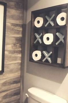 a bathroom with toilet paper on the wall next to a framed photo and wooden planks