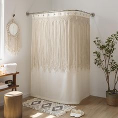 a bathroom with a shower curtain, rug and potted plant on the floor in front of it