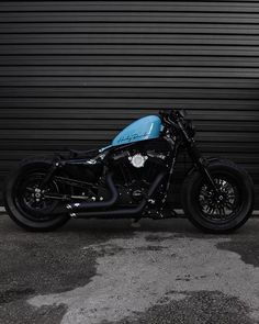 a black and blue motorcycle parked in front of a garage door on the side of a road