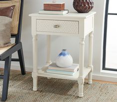 a white table with a blue and white vase sitting on top of it next to a chair