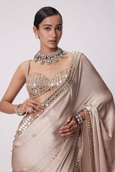 Beige satin saree with a mirror embroidered border. Paired with a padded mirror embroidered blouse. - Aza Fashions Party Pre-draped Saree With Mirror Work In Art Silk, Glamorous Designer Pre-draped Saree For Navratri, Festive Embellished Art Silk Saree, Designer Wear Embellished Art Silk Saree, Embellished Art Silk Saree For Designer Wear, Designer Embellished Art Silk Saree, Bollywood Style Embellished Art Silk Blouse Piece, Embellished Art Silk Saree For Reception, Embellished Art Silk Pre-draped Saree For Festivals