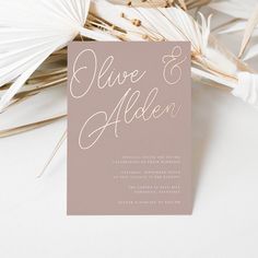 the wedding stationery is laid out on top of some palm leaves and paper fans