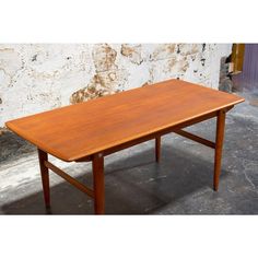 a wooden table sitting on top of a cement floor next to a white brick wall