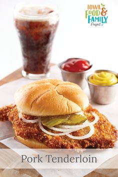 pork tenderloin sandwich with pickles, onions and ketchup on the side