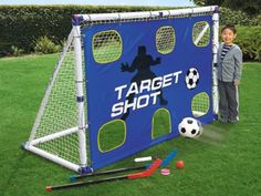 a young boy standing next to a soccer goal with balls and sticks in front of it