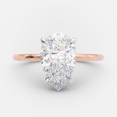 a rose gold engagement ring with a pear shaped diamond in the center, on a white background