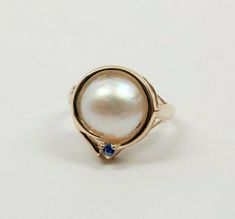 14K yellow gold Mabe pearl and sapphire accent ring, 12 mm 1/2 pearl with bright blue sapphire accent to top circa 1990, ring size 6, weight 3.6 grams Stock # BRT2027 Most rings are sizable for a small fee. If the ring you are considering is the incorrect size contact us for a quote. This listing contains photographs of the actual item you will receive. Our items are in excellent condition with little or no signs of wear and many are one of a kind pre-owned estate finds. Please look closely at t Mabe Pearl, Boston Ma, Bright Blue, Blue Sapphire, Boston, Gemstone Rings, Sapphire, Ring Size, Yellow Gold