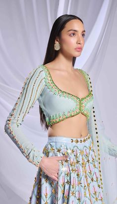 Like a breath of fresh air, our ice blue sequin-printed lehenga comes with pockets! Adorned with opulent gold embellishments, pearls, crystals and 3d flowers. Paired with a full-sleeve embroidered blouse with pearls, crystals, pink enamelled drops and glass stones along with a matching tulle dupatta filled with acrylics, crystals and a pearl border. Designer Hand Embellished Blue Dupatta, Blue Hand Embellished Sharara For Reception, Blue Hand Embellished Choli For Reception, Blue Hand Embellished Fitted Sharara, Festive Blue Hand Embellished Choli, Festive Blue Hand-embellished Choli, Blue Hand Embellished Choli With Traditional Drape, Hand Embellished Blue Choli With Traditional Drape, Traditional Blue Hand Embellished Choli