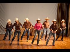 a group of people that are standing on a wooden floor in front of a curtain