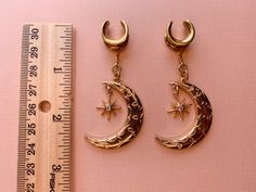 2g (6mm) - 1 3/16 (30mm) Gold Tone Crescent Moon & Star Saddles Drop Dangle Earrings Gauges/Earplugs Plugs.PLEASE read section regarding sizing before purchasing as due to sensitive nature of my products (body jewelry) as I cannot accept returns or exchanges. The details:-316L stainless steel saddle. -Features gold tone alloy crescent moon and 18k gold plated star with zircon center. -All earrings are assembled by hand and sold in pairs.-Available from 2g (6mm) to 30mm.-Each earring (not includi Celestial Star Jewelry For Festival, Celestial Star-shaped Festival Jewelry, Celestial Festival Star Jewelry, Adjustable Celestial Cartilage Earrings, Internally Threaded Crescent Piercings For Gift, Internally Threaded Crescent Piercings As A Gift, Celestial Crescent Cartilage Earrings, Celestial Adjustable Body Jewelry For Gifts, Adjustable Celestial Style Body Jewelry For Gifts