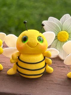 three yellow and white bees sitting next to each other on a wooden table with flowers in the background