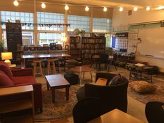 a library with tables, chairs and couches filled with lots of bookshelves