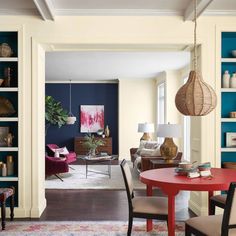 a living room filled with furniture and a red table in front of a blue wall