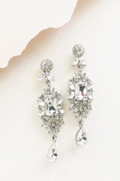 two pairs of crystal earrings on top of a piece of white paper next to each other